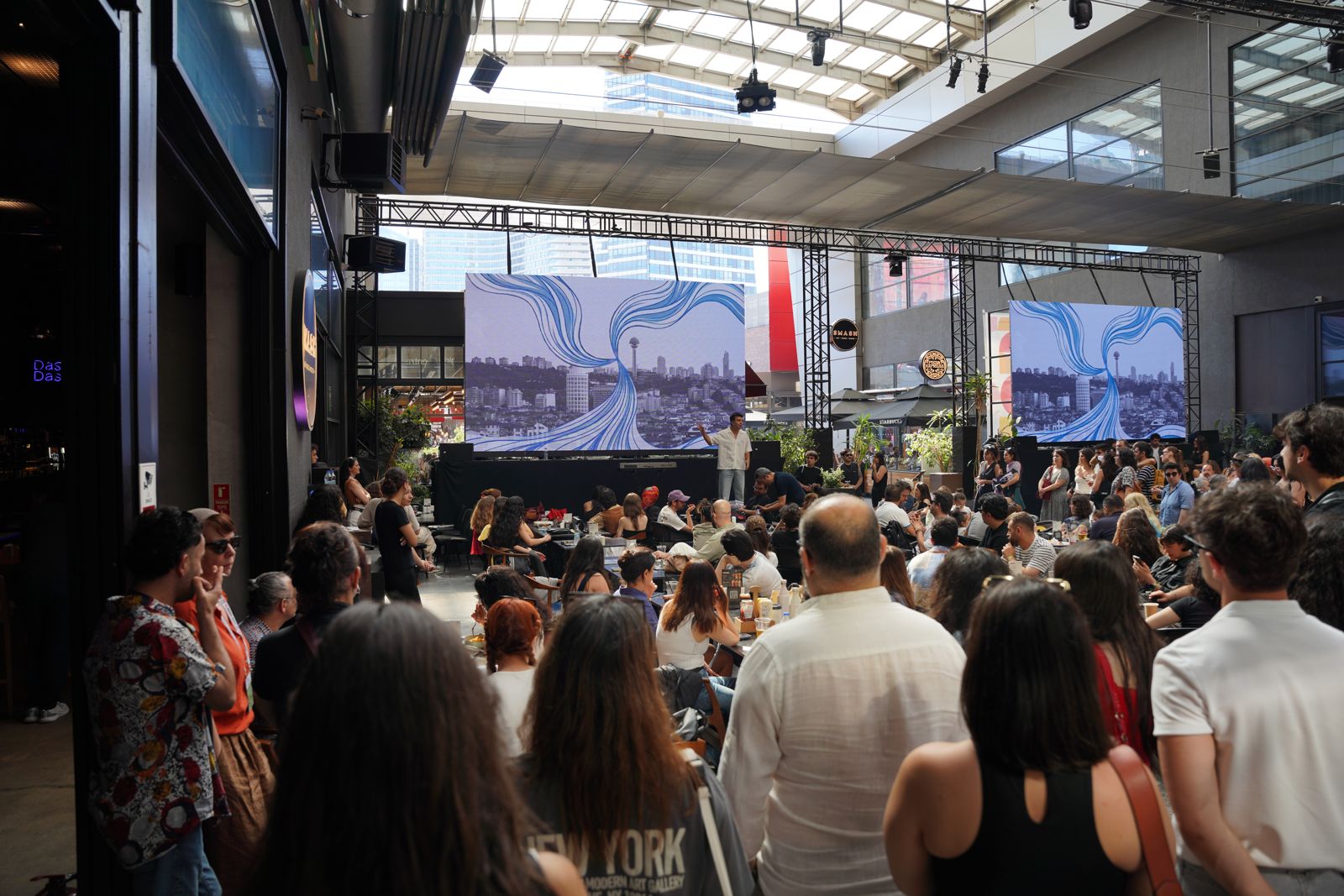Festival alanında ayakta ve oturarak sahneyi izleyen seyirciler